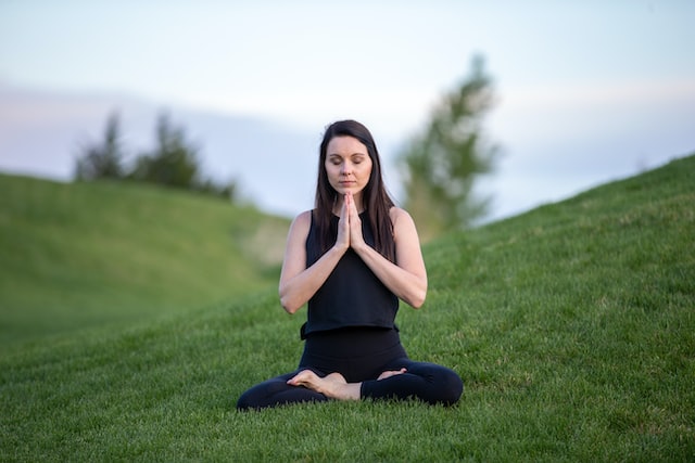 Image of woman in yoga pose sitting on grass