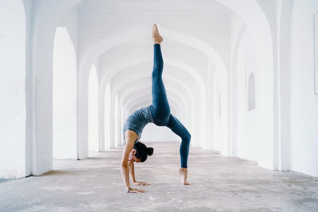 Image of woman in standing yoga pose in white corridor